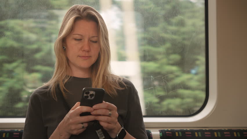 girl sits on a train and works on her phone. A young woman plays games or watches videos on her smartphone while riding the subway. - Powered by Shutterstock - Get 15% off with code: PIKWIZARD15
