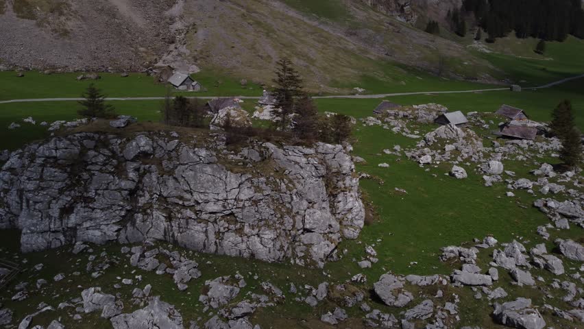 An aerial view of a rock in a field with houses and roads in Switzerland