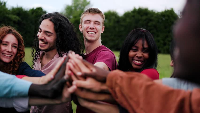 Team of people stacking hands in circle in summer day. Group of friends celebrating together at park city. Support, collaboration and win concept