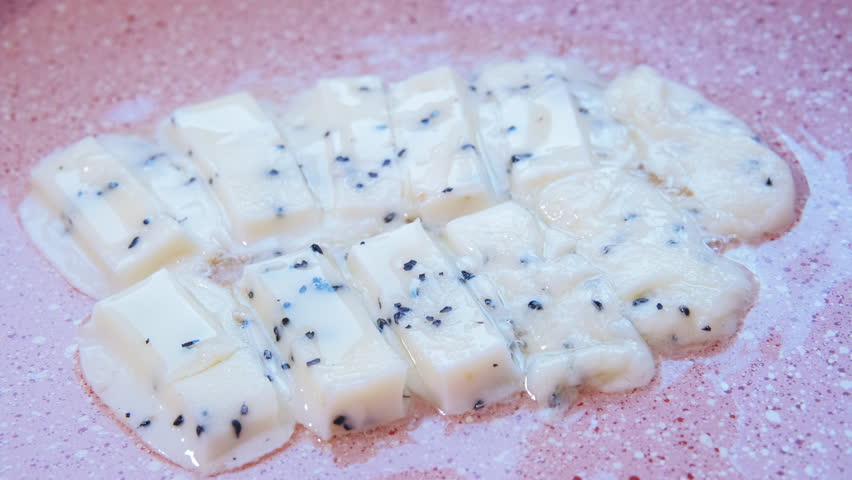 Close-up view of herb cheese melting in a sizzling frying pan, The strings of cheese crisping and bubbling.  Cooking , culinary, vegetarian food concepts. 4K Timelapse video with sound.