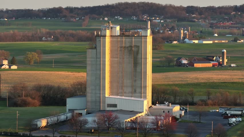 Industrial factory with trucks on gate during sunset time in rural area of Pennsylvania, USA. Aerial Orbit wide shot.