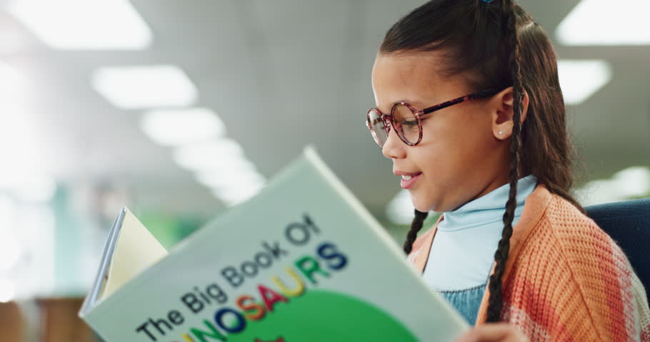 Reading, child and student with book in library for information, learning or knowledge on dinosaurs. Scholarship, education and young girl with textbook for growth, development or project research