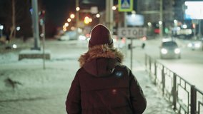 First-person view of a woman in a winter coat with a fur hood, walking at night in an urban setting. Blurry city lights and moving cars are visible in the background - Powered by Shutterstock - Get 15% off with code: PIKWIZARD15