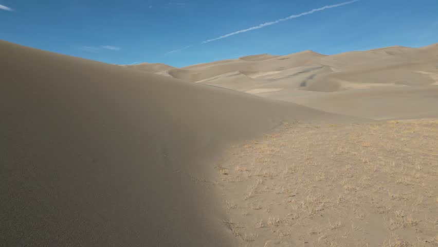 A drone footage over the Great Sand Dunes National Park and Preserve with blue sky in the background in Colorado, USA