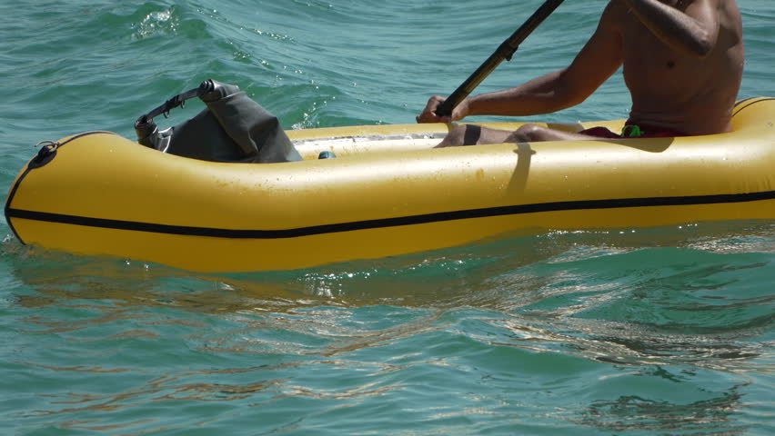 Man Rowing Inflatable yellow Boat. Pack raft in calm blue water. Sea Active Vacation Holiday