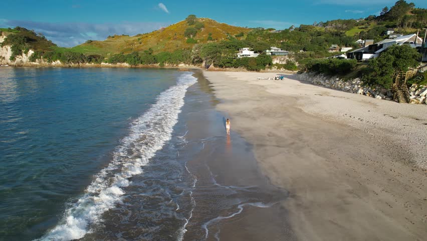 Woman Tourist Walking In The Sandy Shore Of Hahei Beach In Coromandel Peninsula, New Zealand - Drone Shot