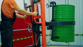 Factory worker in uniform lifts green barrel of chemicals using hydraulic jack. Ensuring safety while transporting hazardous materials. Industrial process showcasing proper handling and transport.  - Powered by Shutterstock - Get 15% off with code: PIKWIZARD15