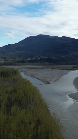 Vertical video of Sandy River Delta At Dusk surrounded by Mountains. Cloudy sky. Fraser River, British Columbia, Canada.