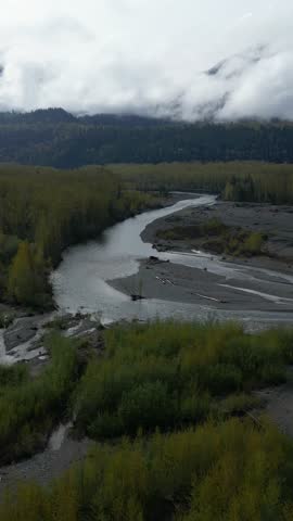 Aerial view of Winding River and Trees surrounded by Mountains. Cloudy Evening. Sunset, Summer. Fraser Valley, British Columbia, Canada.