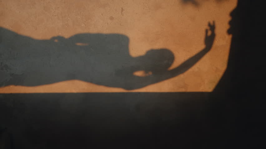 Sensual woman shadow moving on old building wall. Unrecognizable girl dancing body sensually at evening sunlight vertically view. Beautiful lady making smooth hands movements reflecting on build wall.