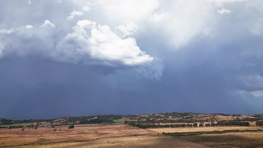 An aerial view of a large storm with heavy rain moving across a rural landscape