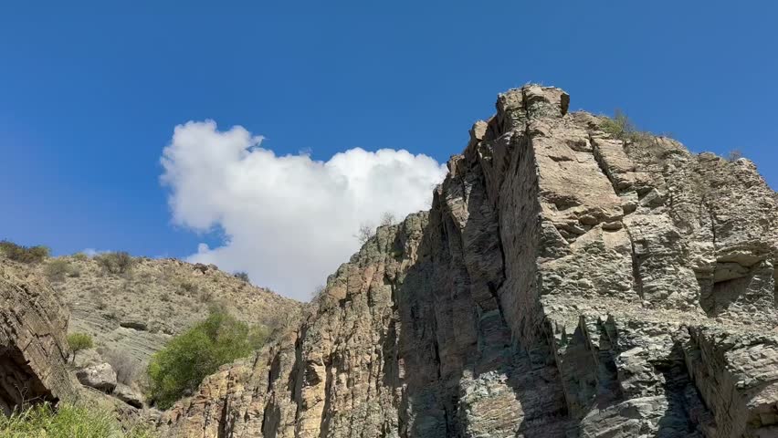 Rocky mountains and cliffs on a sunny summer day captured by low-angle footage.