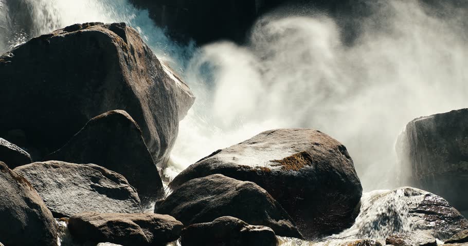 A scenic view of the water of a waterfall cascading on rocks making big splash on a sunny day