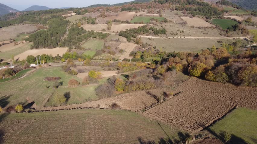 An aerial drone view of ploughed fields under a blue sky on a sunny day