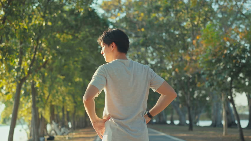 Attractive asian man jogging in the park on a background of trees with sunlight, Fitness Man Running, Training Run Workout.