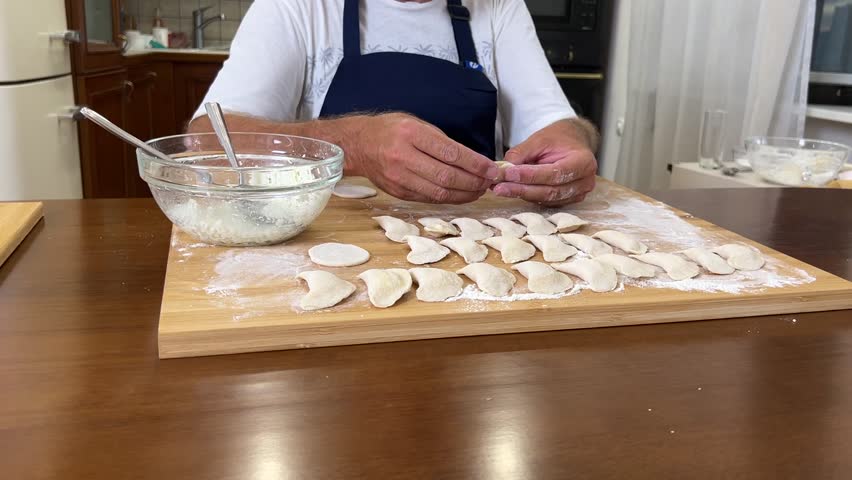 Cooking dumplings, empanadas, vareniki, perogies at home, the man prepares lunch.