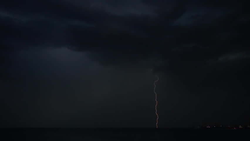 Flashes of lightning in the night sky among thunderclouds.
