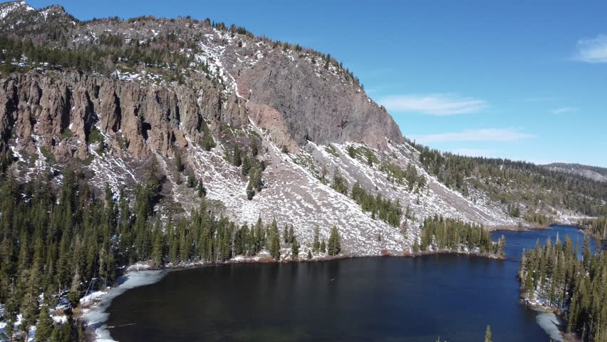 Drone footage flying over Lakes Basin towards mountain side in Northern California's Sierra Nevada mountains with bridge
