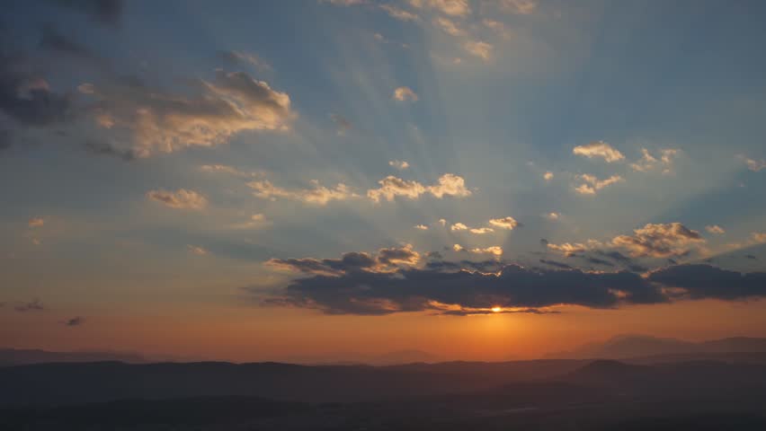 A time-lapse of the golden sun hiding behind the horizon and mountains