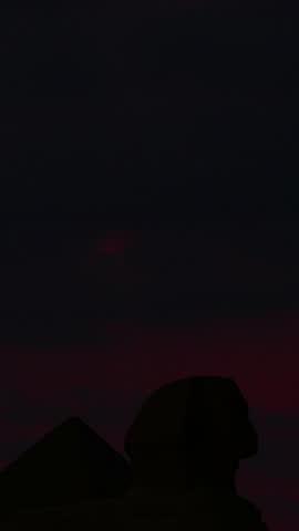 Sphinx located in the middle of the amazing and ancient pyramids in Egypt, with clouds and sun at dawn in time lapse.