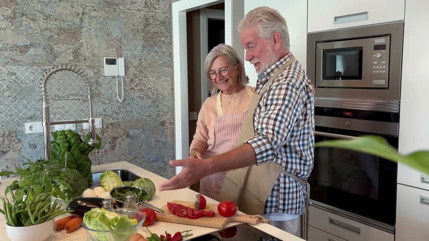 Tender senior couple at home preparing vegetables together. People in the kitchen preparing dinner. Elderly pensioners enjoy a peaceful retirement