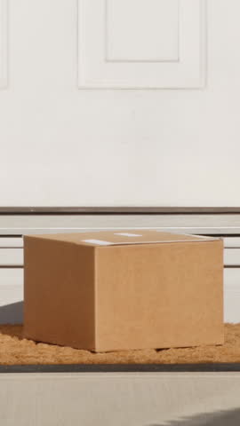 Vertical view of a man picking up a package from outside his front door.	