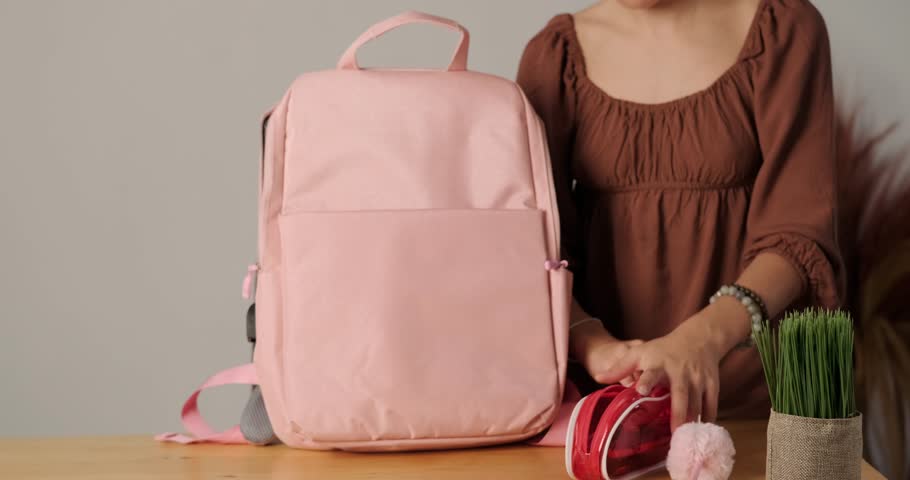 Medium shot of teenage girl packing her backpack to go to school. Mom comes to her and gives her a lunch box with food. Back to school. Morning preparations for school.