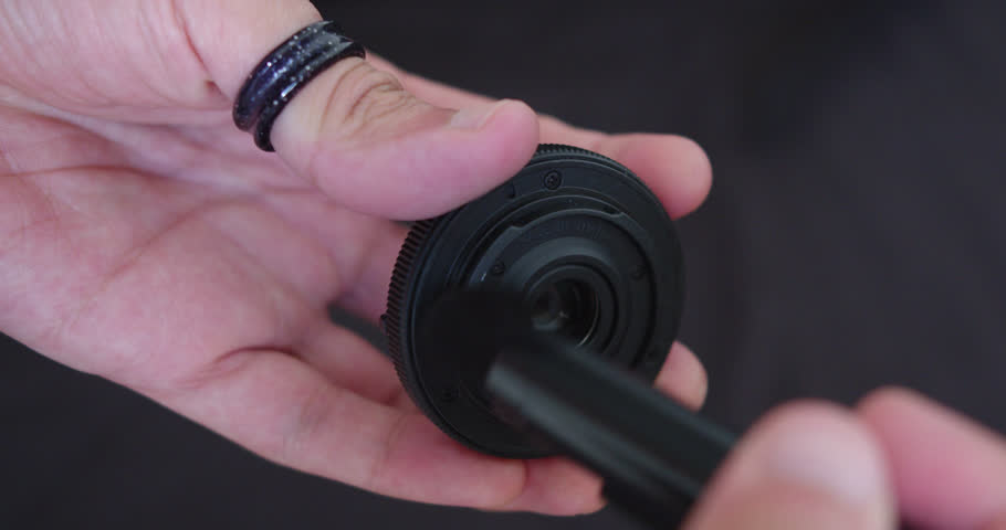 Beautiful close up slow motion shot cleaning a camera lens with a small brush to remove dust and lint inside a room.