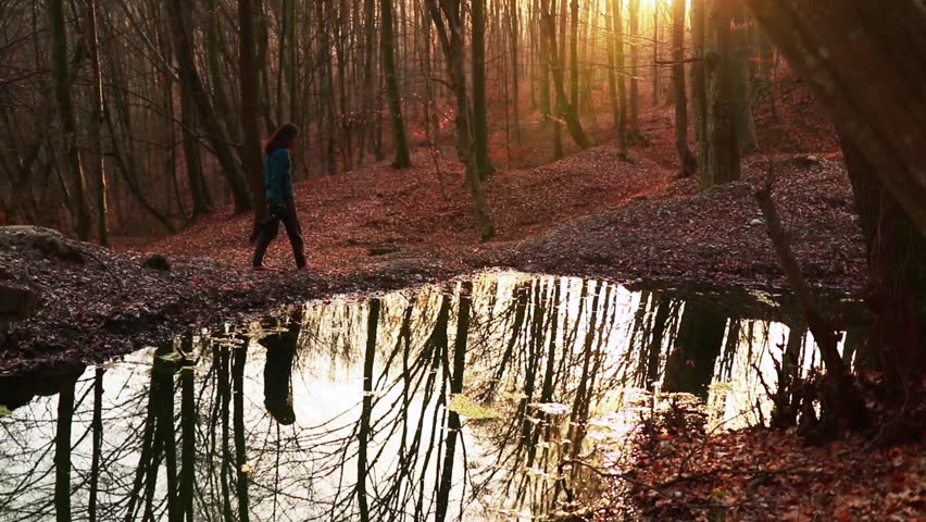 A photographer walking in the orange autumn forest next to the river