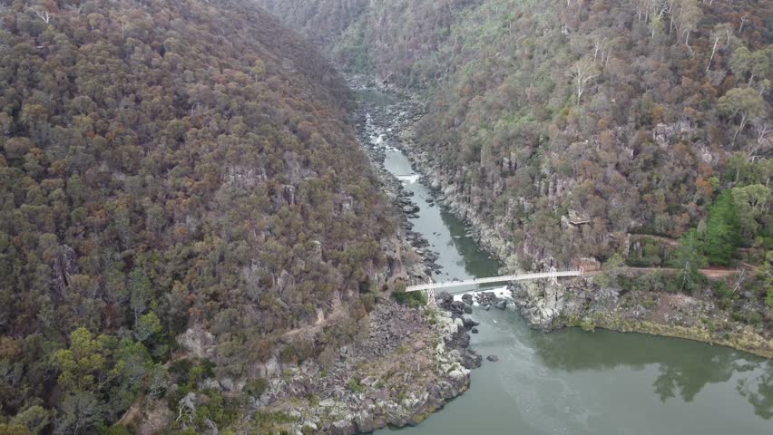4K Aerial view of a Gorge with footpaths, a suspension bridge and a small waterfall in an Australian National Park