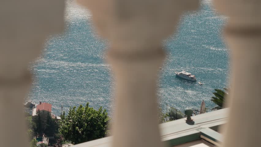 A ship floats on the Mediterranean Sea as seen through a picturesque balcony in Ravello, Italy.