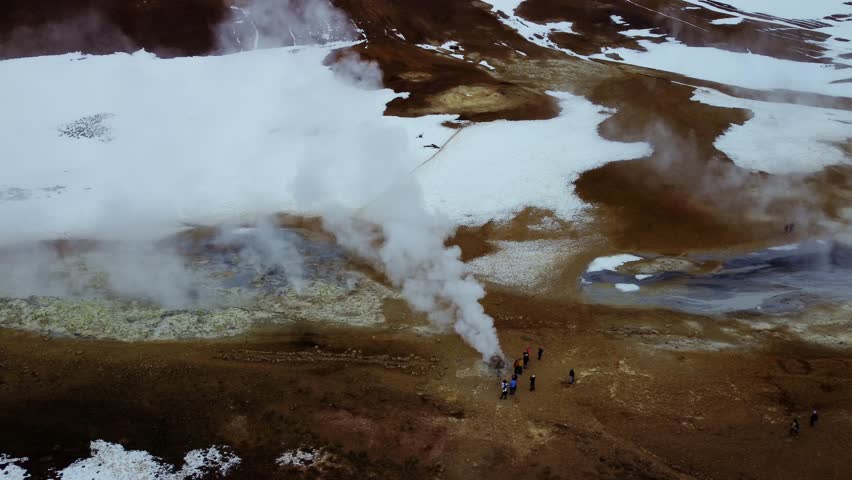 Hot springs and geysers with smoke that smell like sulfur in the west of Iceland near Reykholt during October in a snowy landscape.