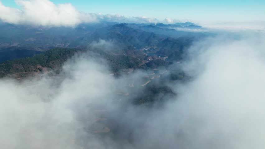 An aerial of clouds over the fjord and big mountains during the daytime