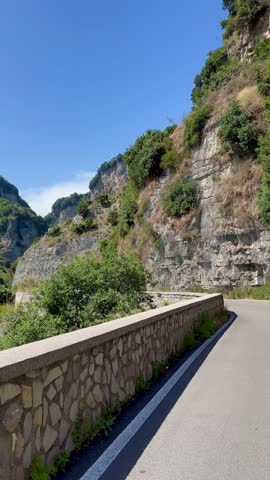 Beautiful footage capturing a motorbike ride along the stunning Italian coastline. The journey showcases the breathtaking scenery of lush greenery, rolling hills, and serene coastal views