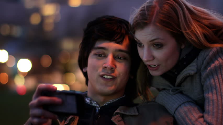 Smart Phone Couple at Night.  Attractive young couple laugh as they find content