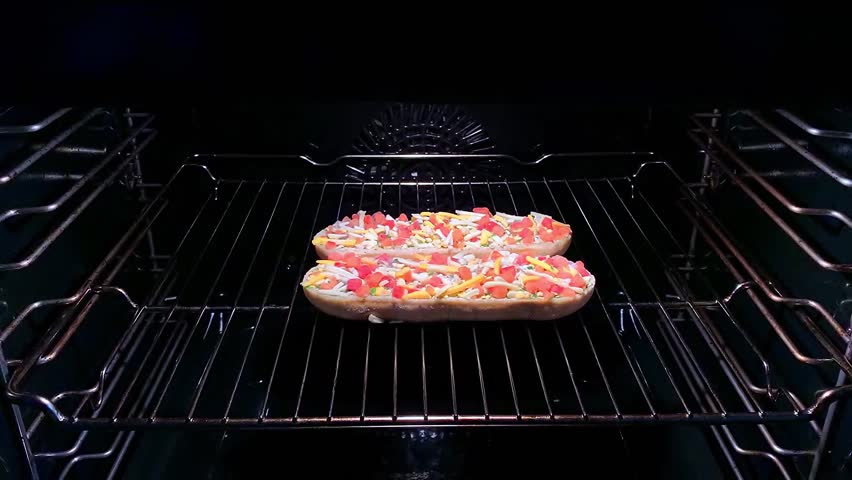Two baguettes with cheese and vegetables in the oven.