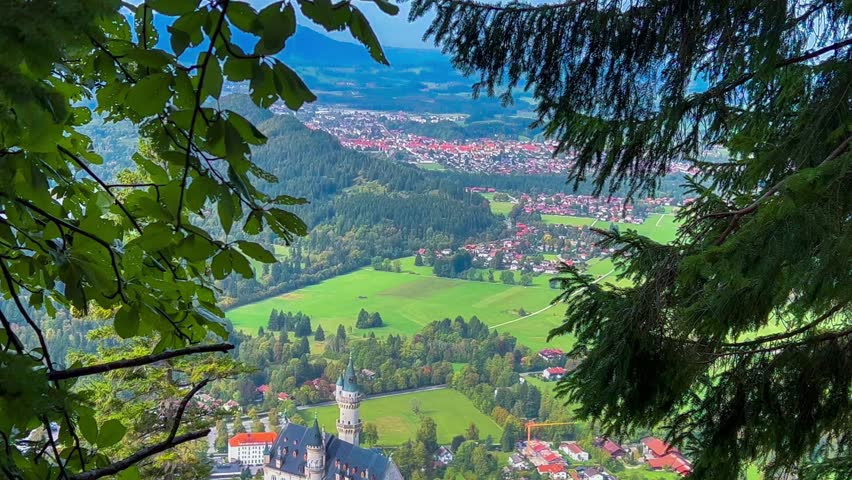 Neuschwanstein castle on Alps background in vicinity of Munich, Bavaria, Germany, Europe. Autumn landscape with castle and lake in mountains covered with spruce forest. High quality 4k footage