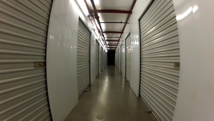 A camera mounted on a dolly rolls down a long corridor past individual public
