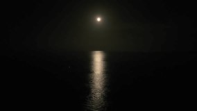 A clear large distinct moon shines over the ocean in an eerie night scene. Night scene. - Powered by Shutterstock - Get 15% off with code: PIKWIZARD15