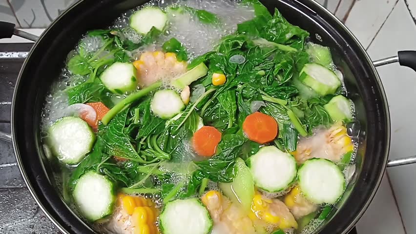 cook sayur bening or clear soup in a pan. contains spinach, corn, carrots and other vegetables. indonesian food