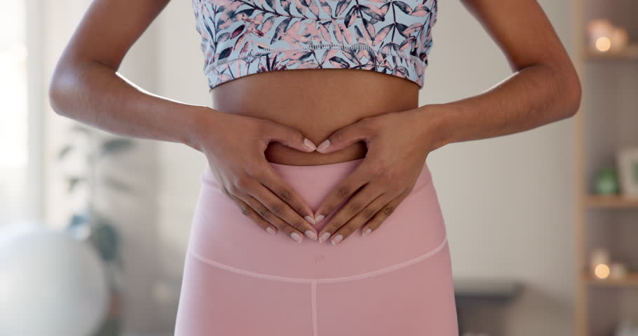 Woman, fitness and heart hands on stomach for wellness, healthy body and self care at home. Yoga, person and holding tummy in love gesture for gut health, lose weight progress and calm in pilates