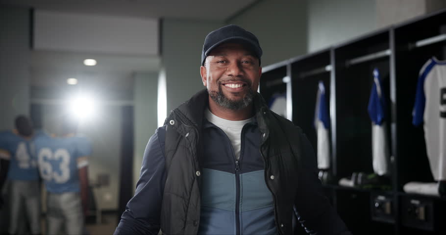 Sports, coach and face of black man with arms crossed for competition, leadership and confidence. Happy, mature manager and portrait with pride in locker room for match, fitness and football game