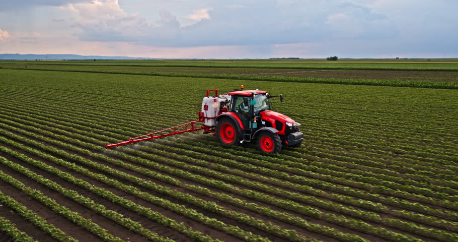 Tractor spraying an industrial soybean crops at agricultural farm