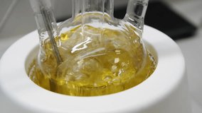 Light liquid is bubbling in a flask under laboratory conditions. Quality control in the laboratory at factory of sparkling wines. Flask is heated with large temperature on the stove in laboratory. - Powered by Shutterstock - Get 15% off with code: PIKWIZARD15