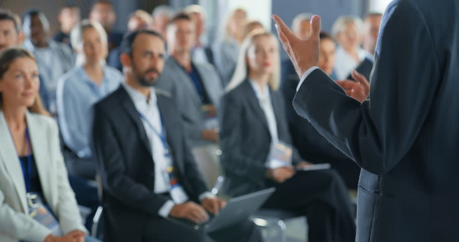 Back View, Focus on Hand Gestures Of Startup CEO Pitching Product Or Service to Room Full of Diverse Investors. Business People Listening To Presentation At International Technology Forum. Slow Motion