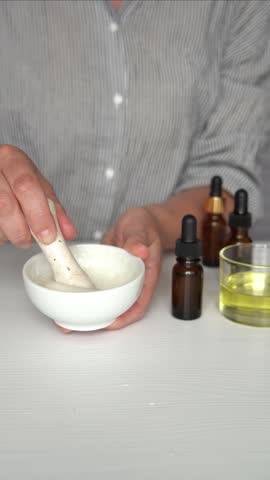 Homemade organic cosmetics, natural skincare products, woman mixes face mask in bowl with natural ingredients and essential oils, vertical video.