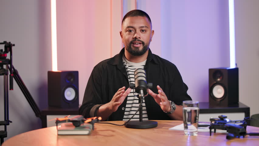 Interview, microphone and podcast presenter with man in recording studio for broadcast or live stream. Creative, media and radio with portrait of influencer speaking on air as talk show presenter