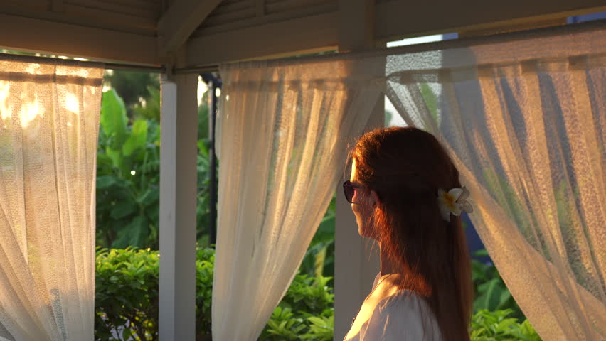 A girl in white comes out of the gazebo