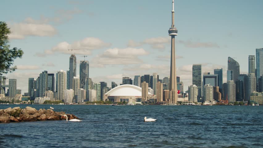 Twilight view of downtown Toronto from an island on Lake Ontario. The CN Tower and skyscrapers create a stunning silhouette against the evening sky.