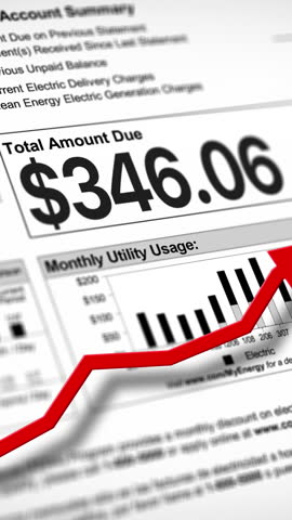 A close-up vertical view of a household electric utility bill rising. Increasing cost of living concept.	 Living paycheck to paycheck concept.
